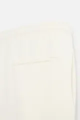 Pantalón negro de corte cropped, con cintura elástica ajustable con cordón, bolsillos laterales y traseros de vivo. El bajo tiene terminación con vuelta.