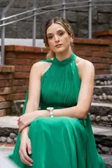Vestido largo de gasa color verde esmeralda, con cuello halter, drapeado en el corpiño y falda plisada. Incluye lazos a los costados del cuello que permiten múltiples formas de uso.