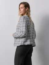 Chaqueta en tejido tweed a cuadrillé blanco y negro, marca Nanette. Cuello a la base y abertura central. Delantera con bolsillos aplicados. Manga larga, puño con botones. Terminación desflecada. Forro interno.