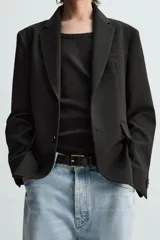 Blazer azul marino de corte recto, confeccionada en tejido con viscosa. Tiene cuello con solapas de muesca, manga larga con puño abotonado, bolsillo de vivo en el pecho y bolsillos de parche en la cadera. El bajo tiene aberturas en la espalda y el cierre es con botonadura frontal.