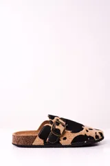 Zuecos con estampado de vaca en tonos camel y negro, con hebilla metálica ajustable y plantilla anatómica.