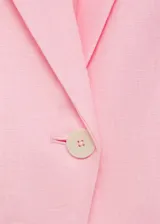 Chaqueta de lino color celeste con cuello de pico y solapas con muesca, cierre frontal con botón, manga larga con puños abotonados, diseño recto, dos bolsillos de ribete en la parte delantera y abertura posterior en el bajo.