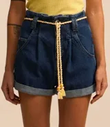Short baggy de jeans azul oscuro, con cintura alta, trabillas, bolsillos y ruedo doblado. Incluye cinturón de cordón color crudo con borlas.