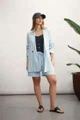 Blazer celeste de lino con solapas de muesca, cierre cruzado con botones, bolsillos delanteros con solapa y corte holgado.