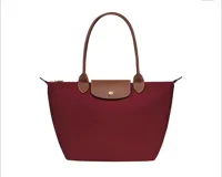 Bolso tote plegable color borgoña, con asas y solapa de cuero marrón.