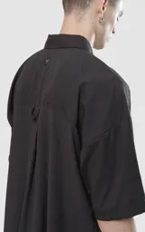 Camisa negra de manga corta con doble bolsillo ojal en delantero, realizada en tejido plano y silueta oversize.