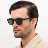 Lentes de sol INVU con montura redonda negra y lentes grises polarizadas.