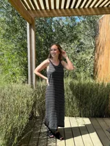 Vestido largo de punto, negro con rayas horizontales blancas, corte recto y sin mangas.