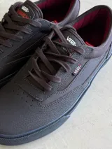 Championes de skate Vans modelo Curren Caples, color negro con detalles en bordó en el interior. Presentan una parte superior de cuero y ante con refuerzos Duracap, suela de goma SickStick y plantilla PopCush.