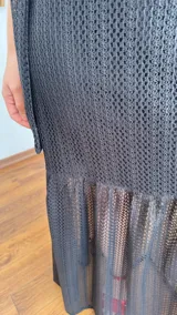 Vestido largo negro de tejido de punto con escote recto y breteles finos. La falda es de encaje transparente. Incluye una bufanda fina al tono.