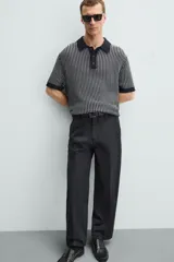 Polo de hombre de corte relajado, tejido de punto de algodón a rayas verticales en tonos gris y negro. Tiene cuello solapa, cierre frontal con botones y mangas cortas.