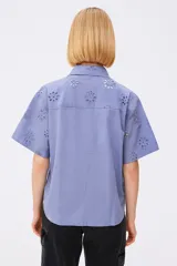 Camisa blanca de algodón con bordado calado de flores, cuello camisero, corte recto y mangas cortas.