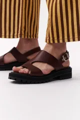 Sandalias marrones de cuero con suela track negra y hebilla plateada.