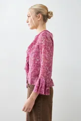 Blusa fucsia estampada con volados, escote en V y mangas largas acampanadas.