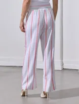Pantalón de lino a rayas verticales color beige y blanco, con pretina ancha elastizada, lazo de ajuste y bolsillos inclinados.