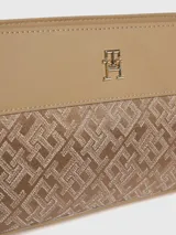 Cartera cruzada Tommy Hilfiger color beige con monograma TH en jacquard. Tiene correa ajustable y logo metálico TH en el frente.
