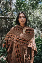 Ruana de algodón color beige con intervención de hilado de cuero de napa ovina color negro. Diseño artesanal con calados geométricos.