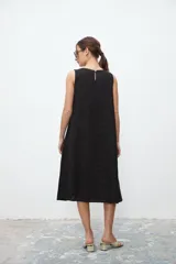 Vestido negro sin mangas, de corte recto y largo a la rodilla.