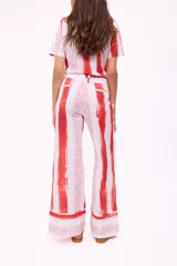 Pantalón de corte palazzo con estampado de rayas verticales rojas y texto ilegible sobre fondo blanco.