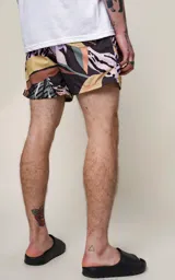 Short de baño negro con estampado de hojas en tonos verde, naranja, amarillo y violeta.