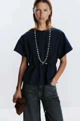 Camiseta color crudo de algodón con cuello redondo, manga corta caída y cintura ajustable con cordón.