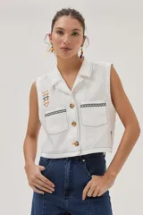 Blusa blanca de lino con cuello camisero, sin mangas, cierre frontal con botones y bordados en el frente.