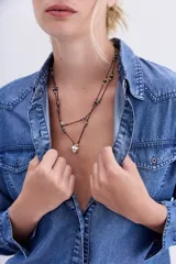 Collar doble de hilo negro con dijes de corazones plateados y cuentas facetadas grises.