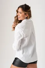 Camisa blanca de algodón con cuello clásico, mangas largas y estampado de texto en negro en el frente.