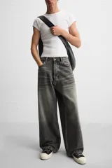 Pantalón de jean negro de corte amplio, con cinco bolsillos, efecto lavado y cierre frontal con cremallera y botón.