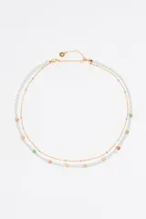 Collar doble con cadena dorada, uno con perlas de río y otro con cuentas de colores y dijes de letras.