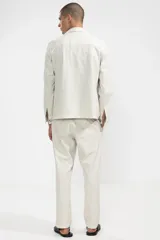 Pantalón de algodón color crema con textura seersucker, corte recto, bolsillos laterales y traseros, cierre con botón y cremallera.