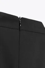 Vestido corto negro con cuello halter y sisas. Detalle de frunces en la falda. Cierre en la espalda con cremallera oculta.