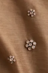 Short mini color beige en tejido liviano con detalles florales elaborados con strass. Modelo de cintura clásica con ribete fino de grosgrain y cierre oculto con cierre de corchete a un lado. Forrado.