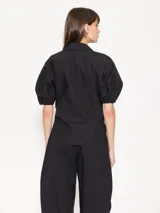 Camisa negra de popelina, de silueta amplia y diseño liviano. Incluye cuello clásico y cierre frontal con botones.