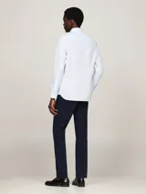 Camisa celeste de corte slim fit con microestampado, cuello abotonado, mangas largas con puños redondeados y logo de Tommy Hilfiger bordado en el pecho.