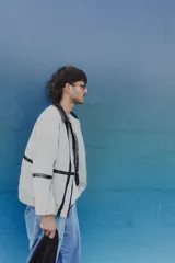 Campera color gris con cierre frontal, cuello alto con detalle de cuero sintético negro, bolsillos laterales con cierre y puños con botón.