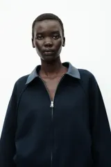 Chaqueta bomber azul marino de tejido de punto con cuello solapa de cuero sintético a contraste y manga larga. Cierre frontal con cremallera metálica.