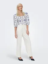 Top corto blanco con estampado de flores azules, cuello cuadrado y mangas cortas abullonadas.