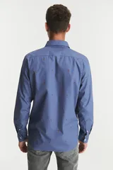 Camisa de manga larga azul con estampado de ciervos en color marrón. Tiene un bolsillo en el pecho y cierre con botones.
