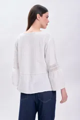 Blusa de muselina color crudo, de corte recto, con cuello redondo y mangas largas acampanadas con detalle de vainillas.