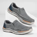 Mocasín Skechers Relaxed Fit Expected Avillo, color gris con detalles en azul y suela blanca. Capellada de lona tejida con efecto deslavado y capas superpuestas de gamuza. Plantilla Skechers Memory Foam.