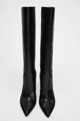 Bota negra de caña alta, confeccionada en cuero sintético, con terminación en punta y tacón fino.