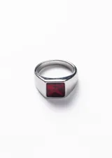 Anillo plateado de acero quirúrgico con piedra roja cuadrada en el centro.