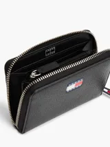 Billetera negra de poliuretano con cierre de cremallera y logo Tommy Jeans engomado en el frente.