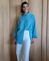 Camisa celeste de corte amplio, con cuello clásico y mangas largas.