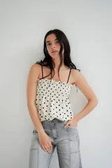 Musculosa blanca con lunares negros, breteles finos y escote recto con fruncido elástico.