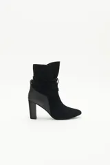 Botas de caña media de gamuza negra, con taco cuadrado y punta fina. Presenta tiras terminadas con borlas que se cruzan y atan alrededor de la caña.