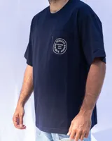 Remera azul marino de algodón con bolsillo en el pecho y estampado circular con la inscripción "Denali Durable Goods. Nacimos para algo".