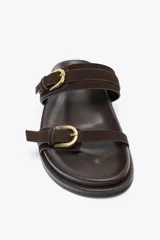 Sandalia plana color marrón chocolate, con dos tiras de ante ajustables con hebillas doradas y suela de goma.