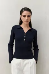 Sweater blanco de punto acanalado con cuello tipo polo y botonadura frontal de botones metálicos. Mangas largas con terminación en pequeñas aberturas.